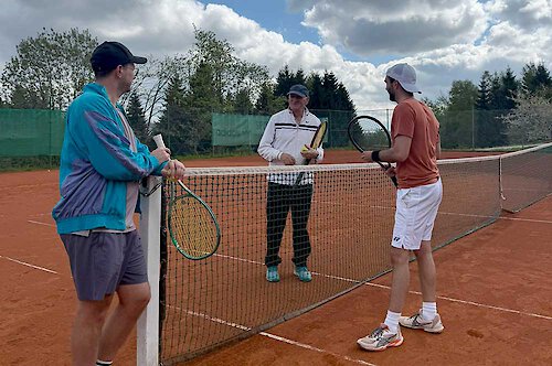 Tennisttrainer unterhält sich mit zwei Spielern Anleitungen zum Tennisspielen in der Schule Mitterdorf